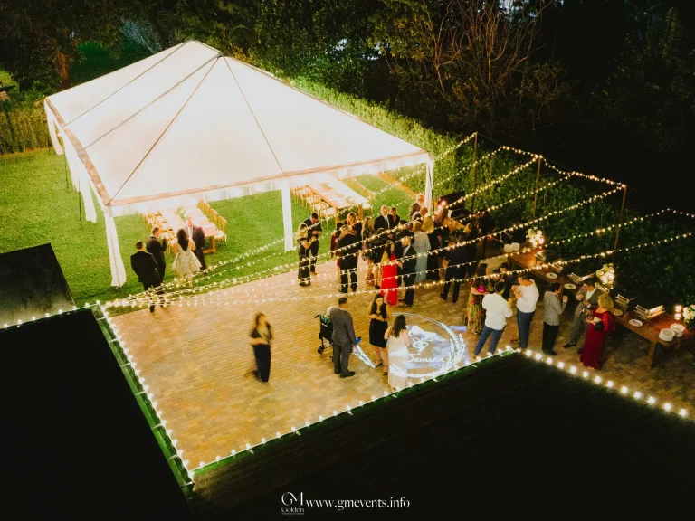 Outdoor tent rental with lighting setup over wood-look event flooring